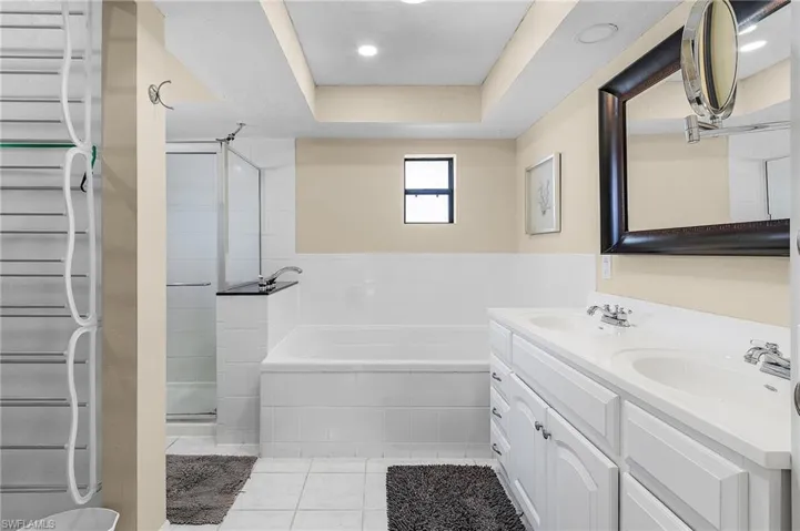 Bathroom with tile patterned floors, vanity, separate shower and tub, a raised ceiling, and radiator heating unit
