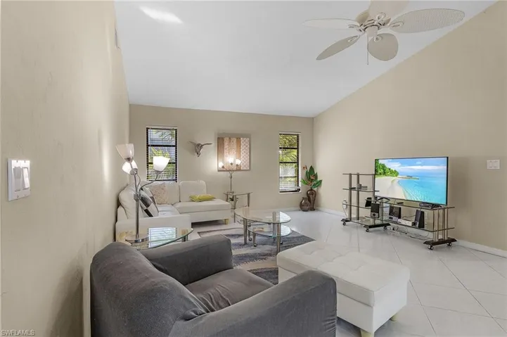 Tiled living room with ceiling fan and lofted ceiling