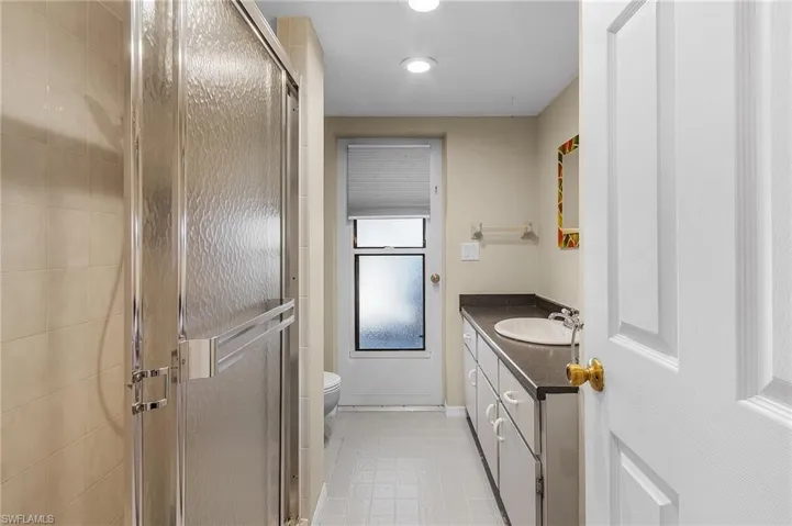 Bathroom with an enclosed shower, vanity, and toilet