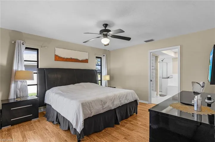 Bedroom featuring ceiling fan, light wood-type flooring, and ensuite bath