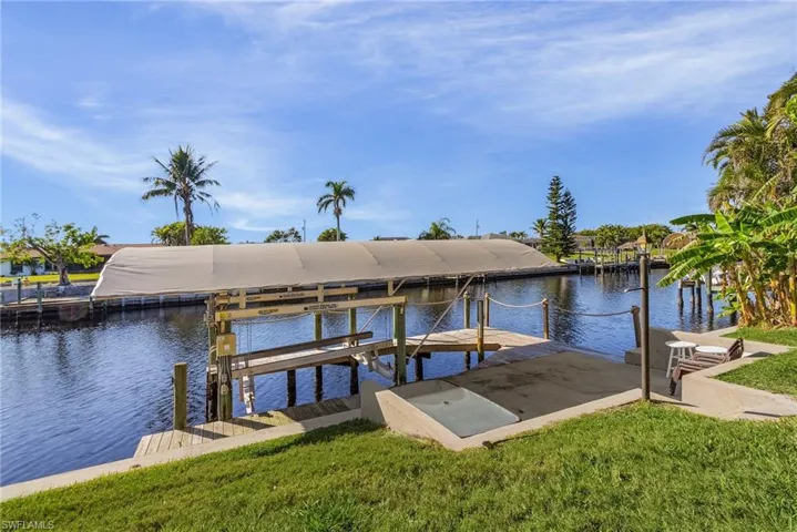 View of dock with a water view and a lawn