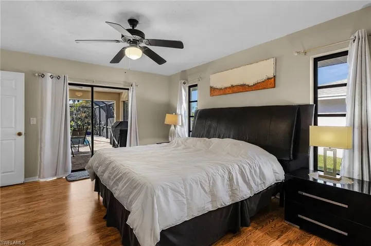 Bedroom with hardwood / wood-style flooring, ceiling fan, access to outside, and multiple windows