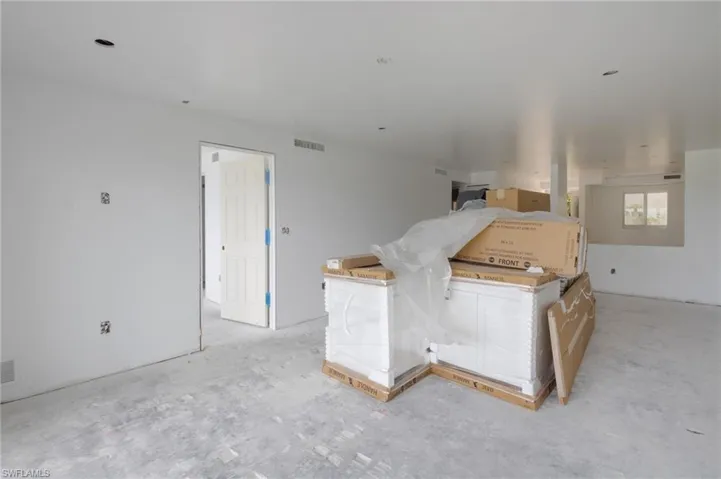 Living area with new quality Kitchen cabinets ready for installation.  The door on the left leads to the Primary Bedroom