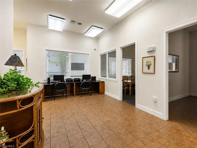 Common area featuring tile flooring, multiple workstations with computer equipment, and access to additional interior spaces