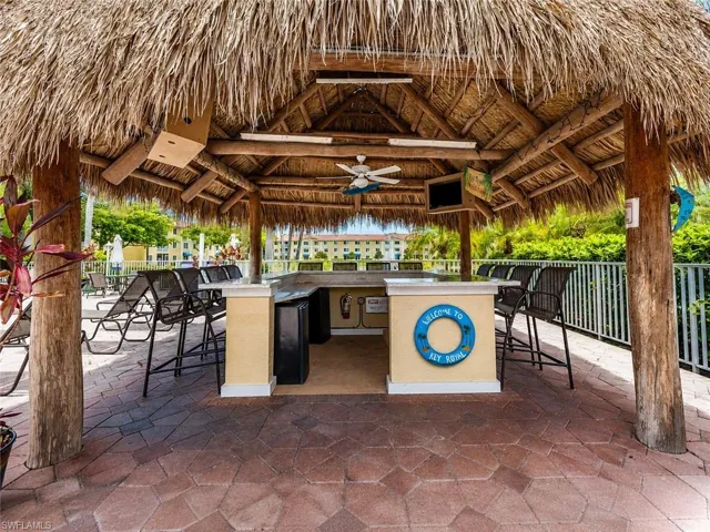 Thatch-roofed cabana featuring exposed wood beams, a built-in bar, and integrated ceiling fans