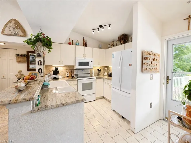Kitchen featuring white cabinetry, light-toned countertops, tile flooring, and vaulted ceilings
