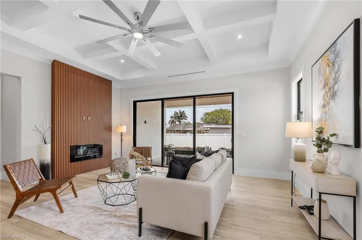 Living area with coffered ceiling, ceiling fan, light wood-style floors, and recessed lighting
