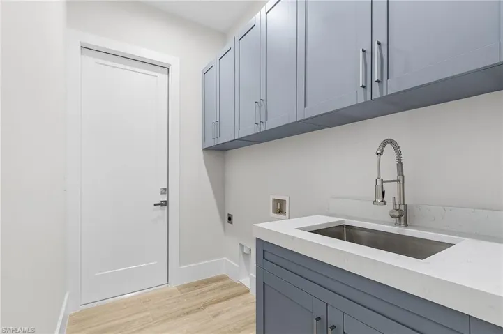 Laundry room with electric dryer hookup, light wood-style flooring, hookup for a washing machine, and cabinet space