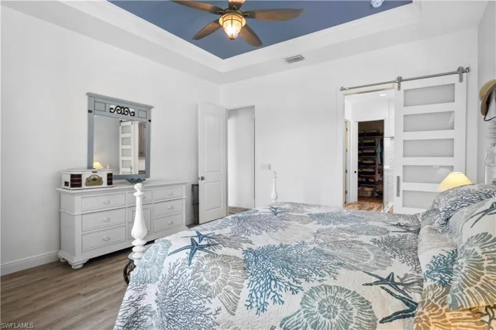 The barn door to the primary bathroom adds a touch of rustic charm and contemporary elegance to the room.