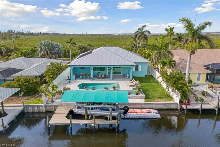 Aerial view of the backside of the home. Together, the pool, canal, and dock create a seamless blend of luxury and nature, offering the ultimate setting for relaxation and outdoor living.