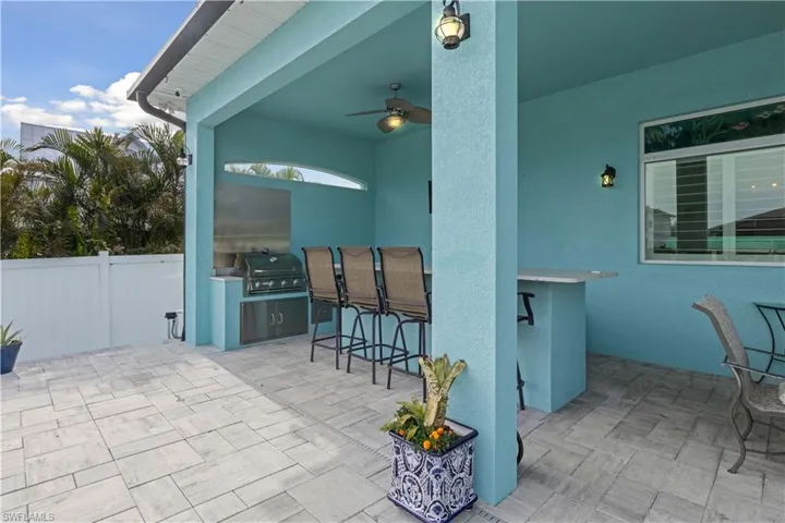 This resort-style outdoor space features a lanai and a custom outdoor kitchen. With built-in grill, refrigerator, and bar seating, it’s the perfect setting for elegant outdoor entertaining or relaxed weekend cookouts.