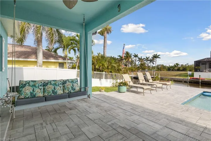 Spacious lanai with a covered seating section, ample room for sunbathing, and a sparkling pool perfect for cooling off or entertaining, complemented by a relaxing swing for enjoying the peaceful surroundings.
