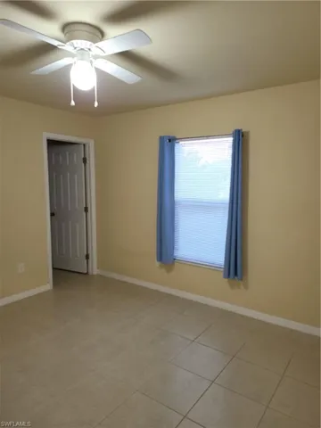 Unfurnished room with light tile patterned floors, a ceiling fan, and baseboards
