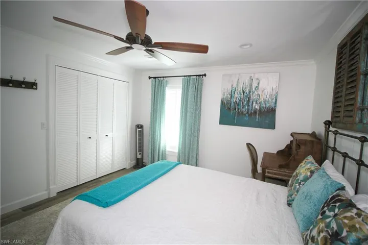Bedroom with ceiling fan, crown molding, wood finished floors, and a closet