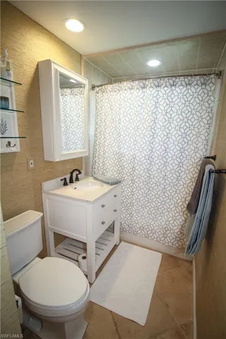 Full bath featuring a shower with curtain, vanity, and light tile patterned flooring