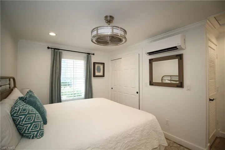 Bedroom with ornamental molding, a closet, a wall mounted air conditioner, and recessed lighting