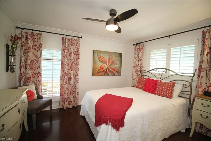 Bedroom featuring crown molding, dark wood-style flooring, ceiling fan, and multiple windows