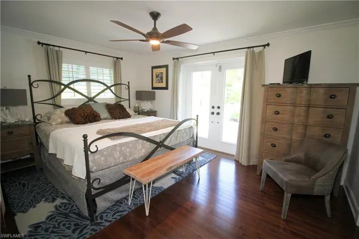 Bedroom featuring french doors, access to outside, ornamental molding, multiple windows, and dark wood finished floors