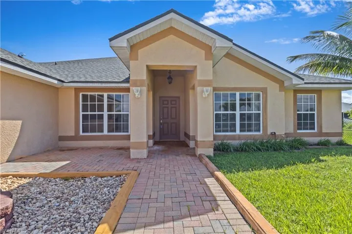 Single story home with stucco siding, a garage, and a front yard with sloping property and an elevation that doesn't require flood insurance!