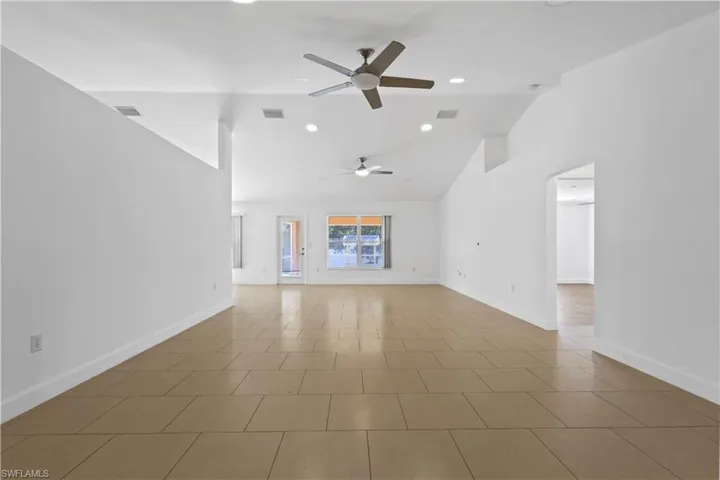 View of the front entry from rear of this amazing great room which has 2 ceiling fans with lights, baseboard moldings and tiled flooring.