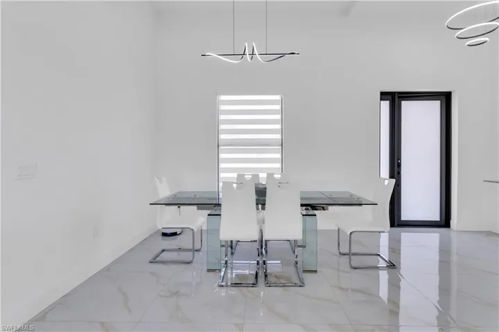 Dining room with a towering ceiling, light tile patterned floors, and an inviting chandelier