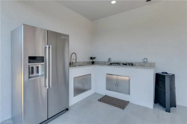 Kitchen with tile patterned flooring, light stone counters, appliances with stainless steel finishes, and sink