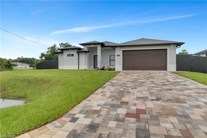 View of front facade featuring a garage and a front lawn