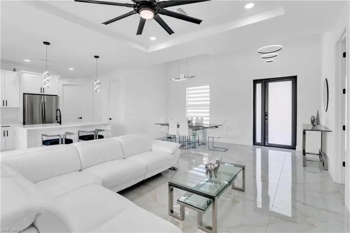 Tiled living room with ceiling fan and a tray ceiling
