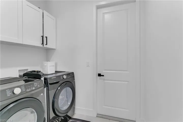 Clothes washing area featuring cabinets and washer and dryer