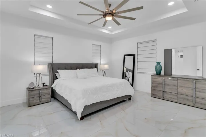 Tiled bedroom featuring ceiling fan and a raised ceiling