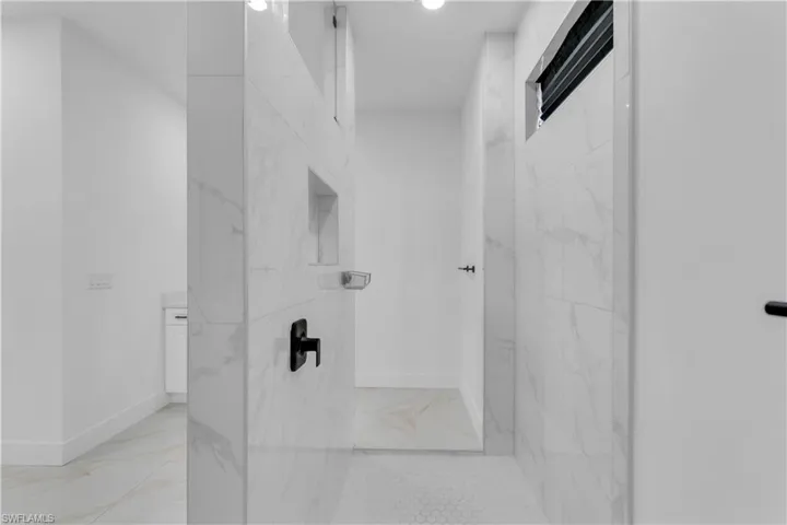 Bathroom with tiled shower and tile patterned floors