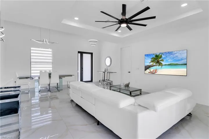 Living room featuring light tile patterned flooring, a raised ceiling, and ceiling fan