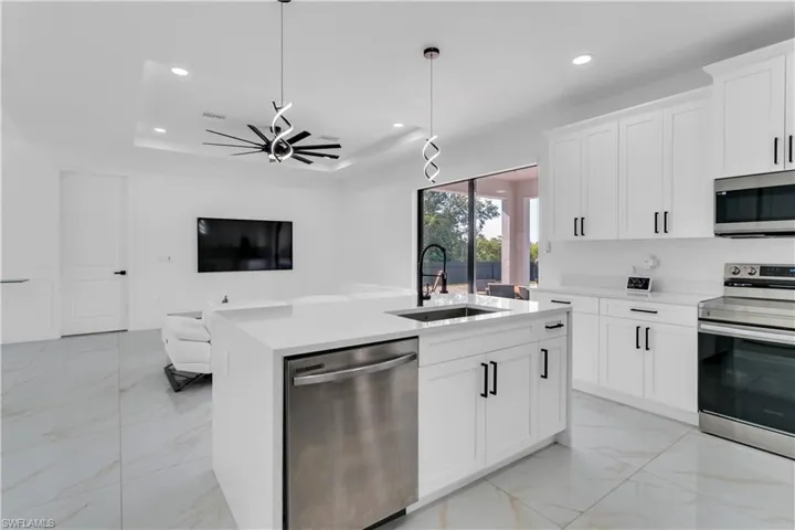 Kitchen with stainless steel appliances, sink, pendant lighting, an island with sink, and ceiling fan
