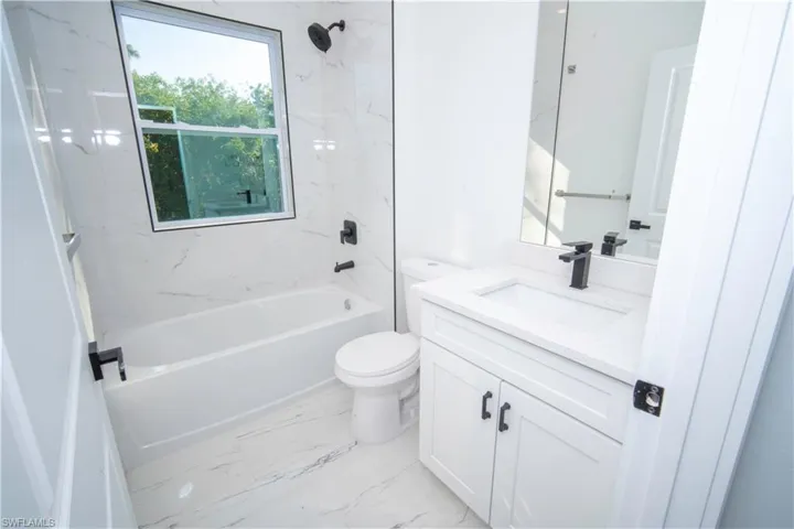 Full bathroom featuring  shower combination, vanity, and light marble finish flooring