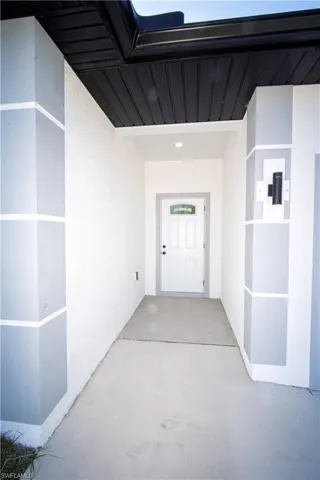 View of exterior entry featuring stucco siding and a patio area