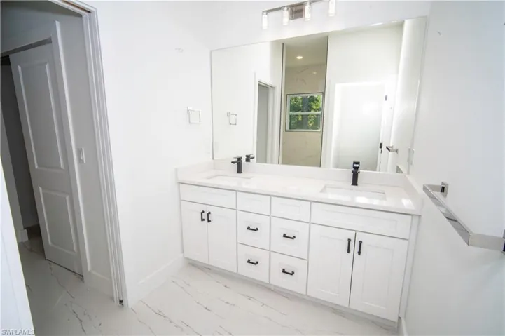 Full bath with double vanity and light marble finish flooring