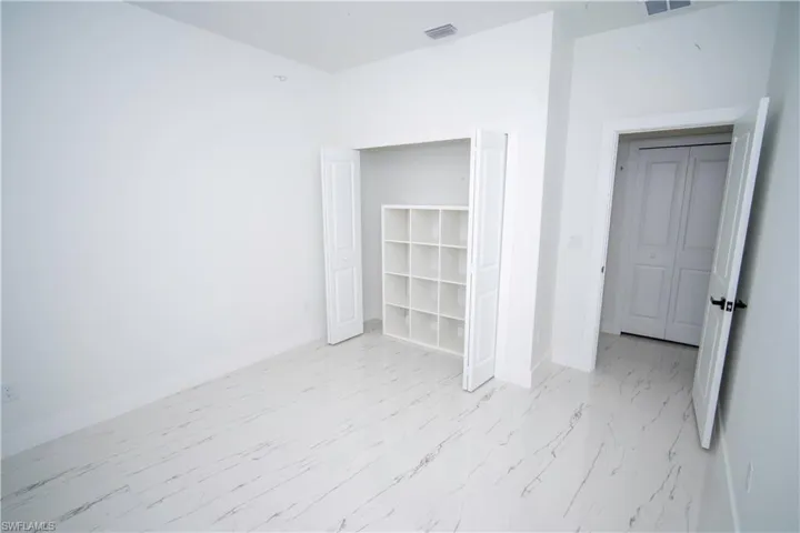 Unfurnished bedroom with baseboards and light marble finish flooring
