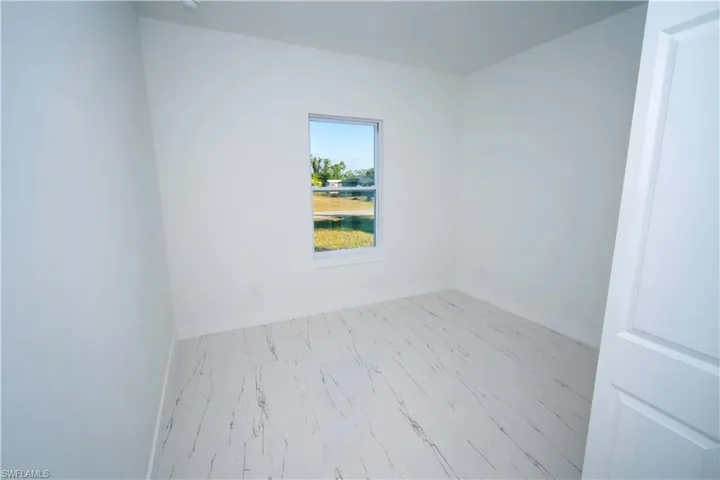 Unfurnished room with baseboards and marble look tile flooring