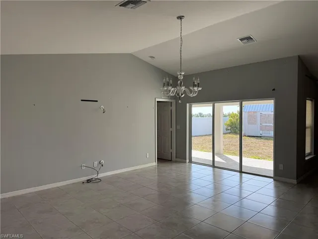 Unfurnished dining area featuring hanging lights, vaulted ceiling, and light tile patterned floors