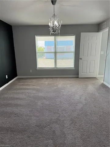 Unfurnished dining area featuring carpet flooring, healthy amount of natural light, suspended lighting, and a textured ceiling