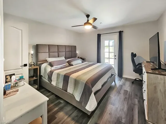 Bedroom with dark wood-type flooring, a ceiling fan, and an office area