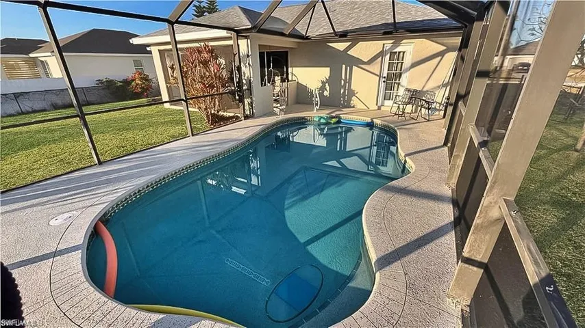 Swimming pool with a lawn, a sunroom, glass enclosure, and a patio