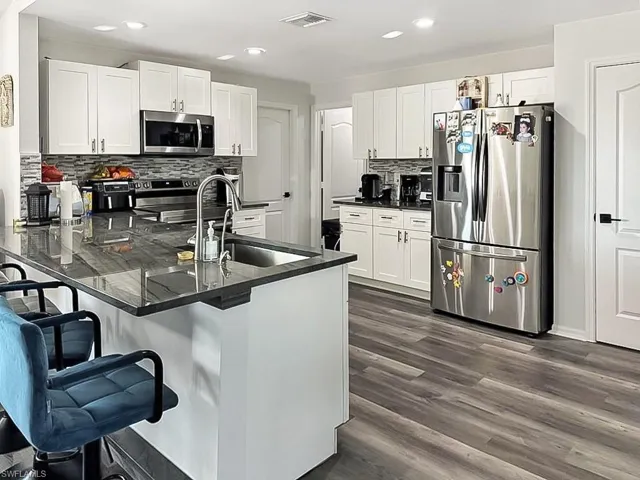 Kitchen featuring a peninsula, white cabinetry, stainless steel appliances, and recessed lighting