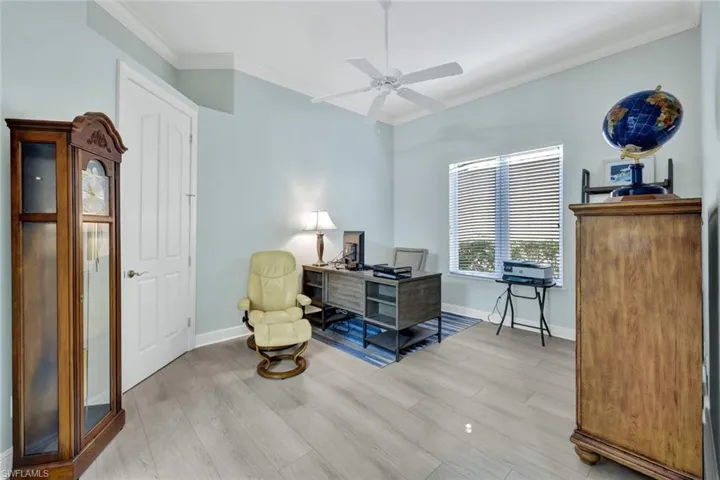 Home office with crown molding, new light vinyl planked flooring, and a ceiling fan