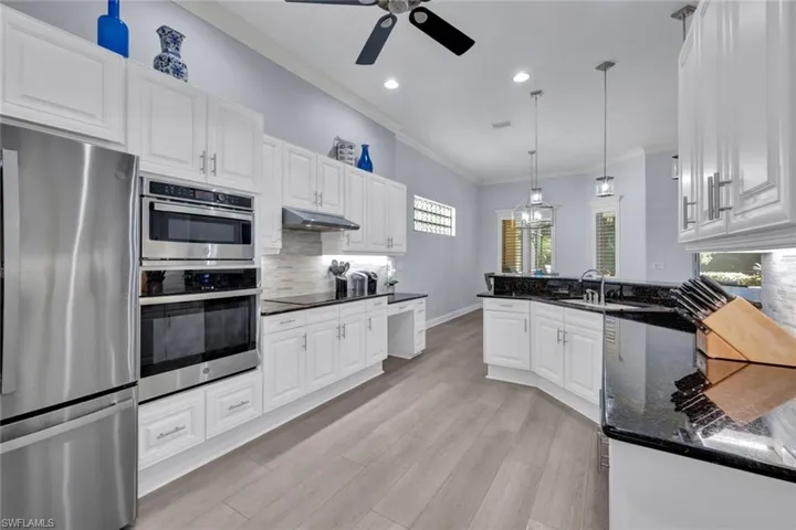 Kitchen featuring stainless steel appliances, granite countertops, healthy amount of natural light, crown molding, and white cabinets