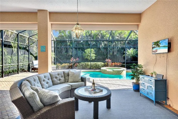 View of patio / terrace under extended covered lanai, a pool with connected hot tub, and an outdoor hangout area