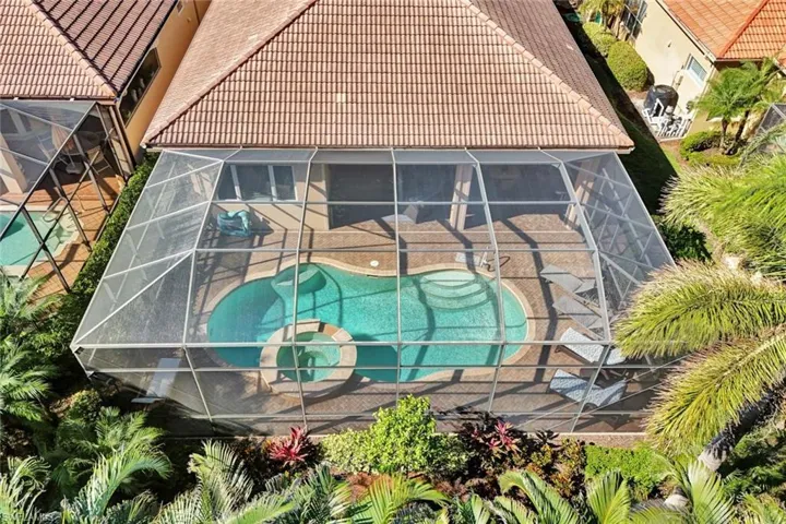 Aerial view of property and surrounding area featuring a pool and lush landscaping