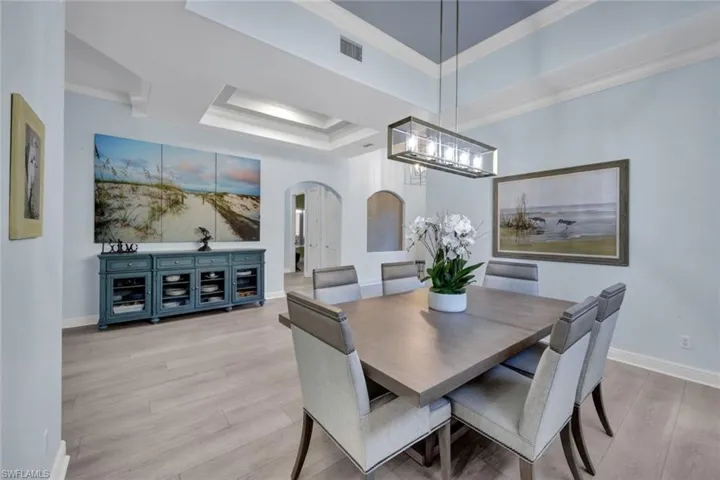 Dining area with a tray ceiling, new light vinyl planked flooring, and crown molding