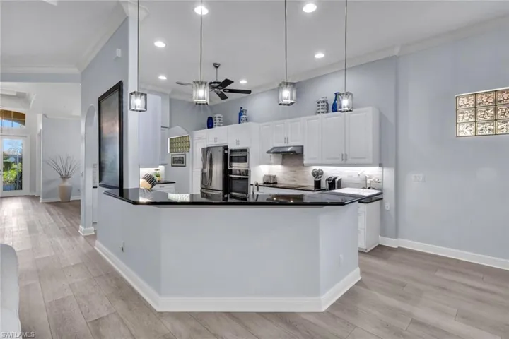 Kitchen with new tasteful backsplash, ceiling fan, new ornamental molding, lighting and white cabinets