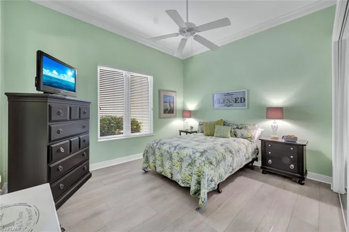 Bedroom with crown molding, light vinyl plank floors, and a ceiling fan